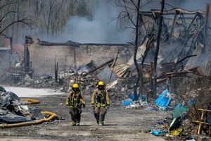 Firefighters walk out of the site of an industrial fire in Richmond, Ind., Wednesday. The former factory site was used to store plastics and other materials for recycling or resale.