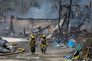 Firefighters walk out of the site of an industrial fire in Richmond, Ind., Wednesday. The former factory site was used to store plastics and other materials for recycling or resale.