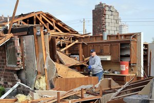 Kent Reynolds removes debris from Wednesday's tornado at his mother-in-law's house on Thursday in Cole, Okla.