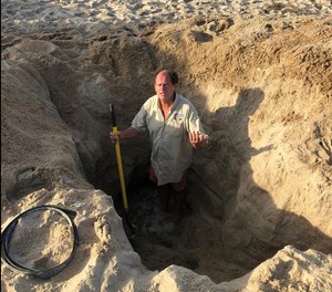 David Elder, ocean rescue director for Kill Devil Hills, North Carolina, stands inside a sand hole that he found on the beach to demonstrate the dangers of sand holes, like the one that claimed the life of a 17-year-old in Norfolk, Virginia, over the weekend.