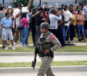 A law enforcement officer walks as people are evacuated from a shopping center where a mass shooting occurred, Saturday, May 6, 2023, in Allen, Texas. Social media posts suggest the shooter had been planning the attack for weeks.