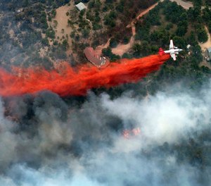 An aircraft lays down a line of fire retardant between a wildfire and homes in the dry, densely wooded Black Forest area northeast of Colorado Springs, Colo., on June 13, 2013. A federal judge said Friday, May 26, 2023, that chemical retardant dropped on wildfires by the U.S. Forest Service is polluting streams in western states in violation of federal law, but said it can keep being use to fight fires.