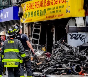 Firefighters and investigators go through the aftermath of a fire which authorities say started at an e-bike shop.