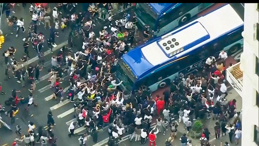 In this image taken from video provided by WABC-TV, a crowd pushes up against a public transit bus as it attempts to move through Union Square, Friday, Aug. 4, 2023, in New York.