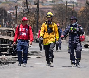Members of a search-and-rescue team walk along a street, Saturday, Aug. 12, 2023, in Lahaina, Hawaii, following heavy damage caused by wildfire.