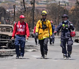 Members of a search-and-rescue team walk along a street, Saturday, Aug. 12, 2023, in Lahaina, Hawaii, following heavy damage caused by wildfire.