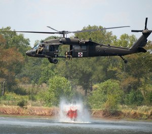 A Blackhawk helicopter fills a 660-gallon basket of water from a farm pond to help battle a wildfire.