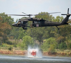A Blackhawk helicopter fills a 660-gallon basket of water from a farm pond to help battle a wildfire.