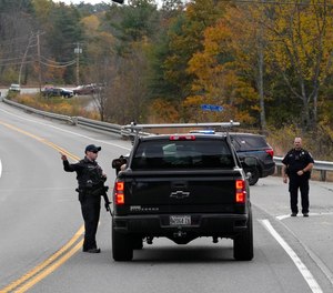 Police officers speak with a motorist at a roadblock.