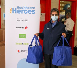 An FDNY EMS member holds her first care package of shelf-stable food, household cleaning and personal care products, as well as over-the-counter medicine, provided by NYC Healthcare Heroes.
