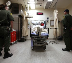 Correctional officers stand watch over an inmate receiving treatment in the emergency room at California State Prison, Corcoran.