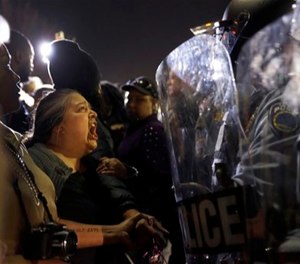 In this Aug. 11, 2014 file photo, a protester yells at police outside the Ferguson, Mo., Police Department during a demonstration sparked by the fatal shooting of Michael Brown.