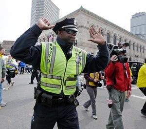 A Boston police officer clears Boylston Street following an explosion at the finish line of the 2013 Boston Marathon in Boston, Monday, April 15, 2013.