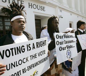 Supporters for a bill that would automatically restore voting rights to convicted felons upon their release from prison hold up signs supporting the bill during a news conference Thursday, Feb. 9, 2006, in front of the State House in Montgomery, Ala.