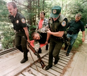 Wounded New Hampshire state trooper Jeffrey Caulder is carried out of the woods still holding his gun in Brunswick, Vt., Tuesday, Aug. 19, 1997, following a gun battle with Carl Drega.