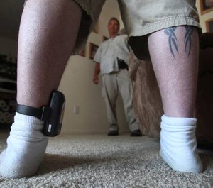 In this photo taken Monday, Aug. 3, 2009, Parole Agent Steve Nakamura talks with a parolee wearing a GPS locator worn on his ankle, in Sacramento, Calif.