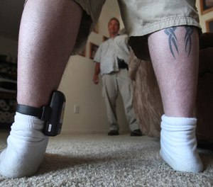 In this photo taken Monday, Aug. 3, 2009, Parole Agent Steve Nakamura talks with a parolee wearing a GPS locater worn on his ankle, in Sacramento, Calif.