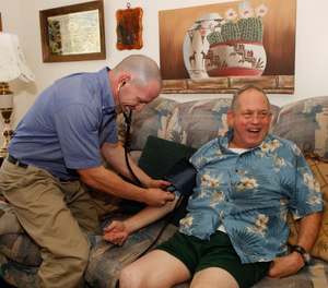 In this Aug. 31, 2011 photo, Eagle County paramedic Kevin Creek checks the blood pressure of James Duke, 64, during a house call to his home in Eagle, Colo.