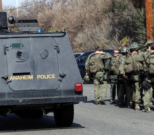An Anaheim, Calif., police armored car and FBI SWAT team members gather near the perimeter of a bank standoff.
