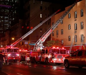 Fire truck ladders are extended to the roof of the site of a three-alarm fire in a four-story building on Manhattan's East side in New York, Wednesday, Sept. 17, 2014.