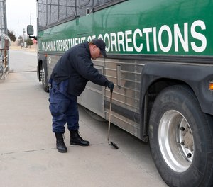 In this Jan. 24, 2013 file photo, a corrections uses a mirror to check the bottom of a transport bus leaving to take prisoners to other locations in the state at the Lexington Assessment and Reception Center, in Lexington, Okla.