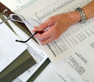 In this Dec. 20, 2011, file photo, medical bills are spread out on the kitchen table of a patient in Salem, Va.