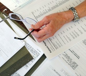 In this Dec. 20, 2011, file photo, medical bills are spread out on the kitchen table of a patient in Salem, Va.