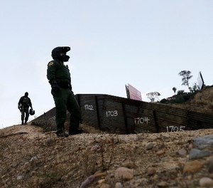 In this Wednesday, June 22, 2016, file photo, Border Patrol agents look over the primary fence separating Tijuana, Mexico, right, and San Diego in San Diego.