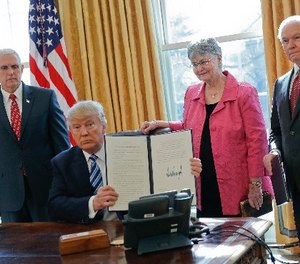 President Donald Trump holds up newly signed executive order aimed at preventing violence against Federal, State, Tribal and local law enforcement officers, Thursday, Feb. 9, 2017, in the Oval Office of the White House in Washington.