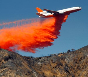 In this Tuesday, Sept. 24, 2013 file photo, a DC-10 airplane tanker drops fire retardant to battle a wildfire in the San Gabriel Mountains in Azusa, Calif. (AP Photo/Nick Ut)