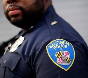 In this March 31, 2016, file photo, a Baltimore Police Department patch is seen on an officer's uniform as he stands on a street corner during a foot patrol in Baltimore.