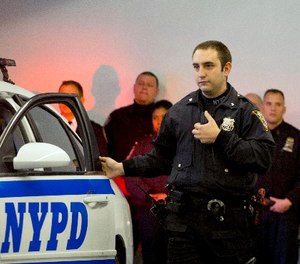In this Dec. 3, 2014 file photo, New York Police Department officer Joshua Jones turns on a body camera attached to his chest during a news conference in New York.