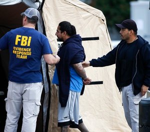 A man is taken into custody by FBI agents Wednesday, May 17, 2017, in Los Angeles. Hundreds of federal and local law enforcement fanned out across Los Angeles, serving arrest and search warrants as part of a three-year investigation into the violent and brutal street gang MS-13.