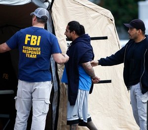 A man is taken into custody by FBI agents Wednesday, May 17, 2017, in Los Angeles. Hundreds of federal and local law enforcement fanned out across Los Angeles, serving arrest and search warrants as part of a three-year investigation into the violent and brutal street gang MS-13. (AP Photo/Jae C. Hong)