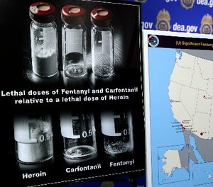 Posters comparing lethal amounts of heroin, fentanyl, and carfentanil, are on display during a news conference about the dangers of fentanyl, at DEA Headquarters in Arlington, Va.