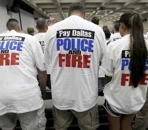 This file photo made Tuesday, Aug. 9, 2016, Dallas police and firefighters fill the gallery for a city council budget meeting at Dallas City Hall in Dallas.