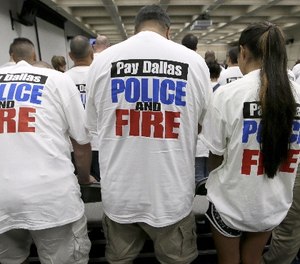 This file photo made Tuesday, Aug. 9, 2016, Dallas police and firefighters fill the gallery for a city council budget meeting at Dallas City Hall in Dallas. (AP Photo/LM Otero)