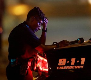 In this July 8, 2016, file photo, a Dallas police officer takes a moment as she guards an intersection in the early morning after an ambush on officers in downtown Dallas.