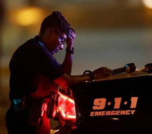 In this July 8, 2016, file photo, a Dallas police officer, who did not want to be identified, takes a moment as she guards an intersection in the early morning after a shooting in downtown Dallas.
