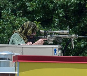 A police sniper sits atop a restaurant near a Wells Fargo Bank, Friday, July 7, 2017 in Marietta, Ga. A man who claimed to have a bomb that could 