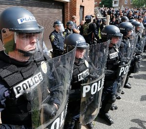Police in riot gear stand ready to clear a path for the members of the KKK to depart a parking garage after a rally Saturday, July 8, 2017, in Charlottesville, Va.