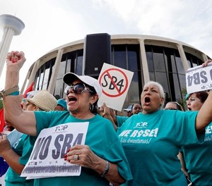 In this June 26, 2017, file photo, Lydia Balderas, left, and Merced Leyua, right, join others as they protest against a new sanctuary cities bill outside the federal courthouse in San Antonio. (AP Photo/Eric Gay, File)
