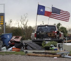 The Texas state flag and American flag wave in the wind over an area of debris left behind in the wake of Hurricane Harvey.
