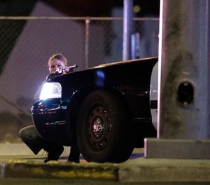 A police officer takes cover behind a police vehicle during a shooting near the Mandalay Bay resort and casino on the Las Vegas Strip, Sunday, Oct. 1, 2017, in Las Vegas. (AP Photo/John Locher)