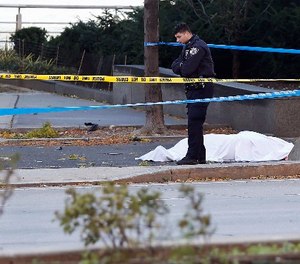A New York Police Department officer stands next to a body covered under a white sheet near a mangled bike along a bike path Tuesday Oct. 31, 2017, in New York.