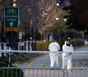 Emergency officials walk near evidence markers on the west side bike path in lower Manhattan, New York, Wednesday, Nov. 1, 2017.