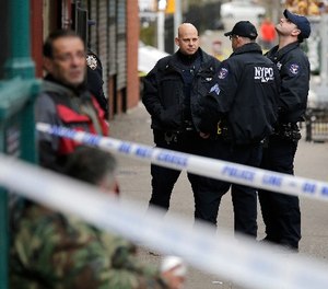 Police officers stand near the scene of a shooting in the Bronx section of New York, Tuesday, Dec. 5, 2017.