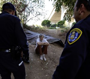 In this Sept. 28, 2017, photo, Stephen Schofield looks on as police officials encourage him to get a Hepatitis A vaccination near where is living along the San Diego River in San Diego.