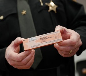Captain Paul Kamphaus, of the Clermont County Sheriff's Office, handles a box of naloxone during an interview, Wednesday, Nov. 15, 2017, in Batavia, Ohio.