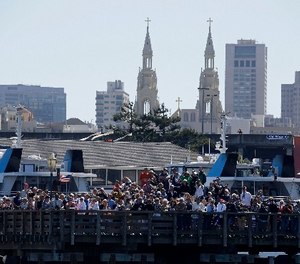 In this Sept. 18, 2013, file photo, spectators at Pier 39 watch Emirates Team New Zealand and Oracle Team USA during the 11th race of the America's Cup sailing event in San Francisco.
